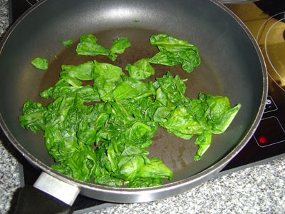 листя шпинату на сковороді